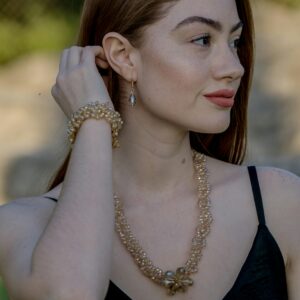 A stylish woman wearing a necklace and bracelet outdoors during the day.