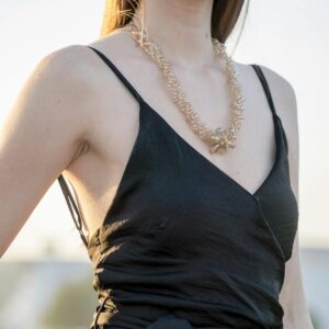 A stylish woman wearing elegant jewelry and a black dress in an outdoor setting.